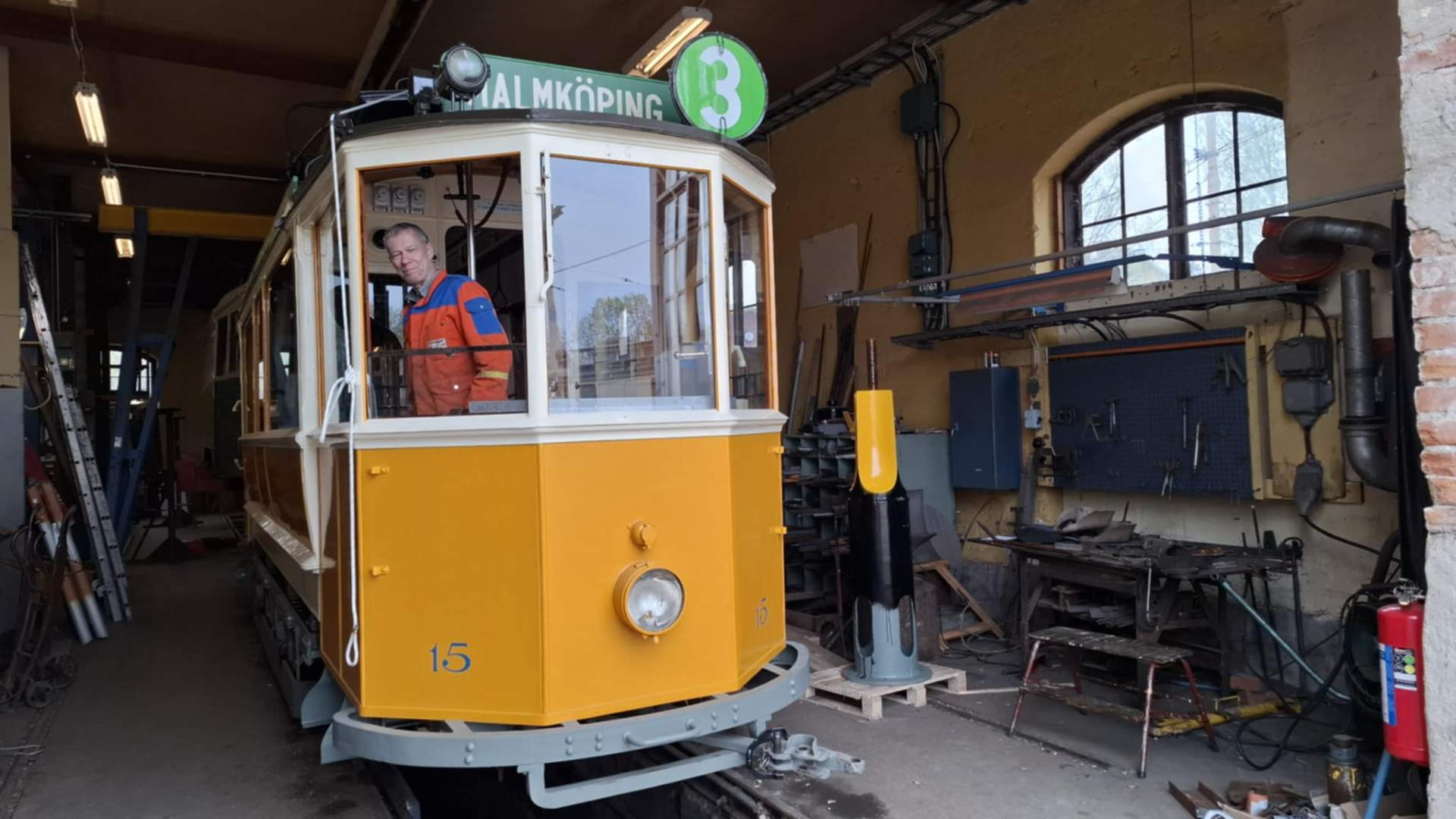 Gul spårvagn nummer 15 i vagnhallen i Malmköping